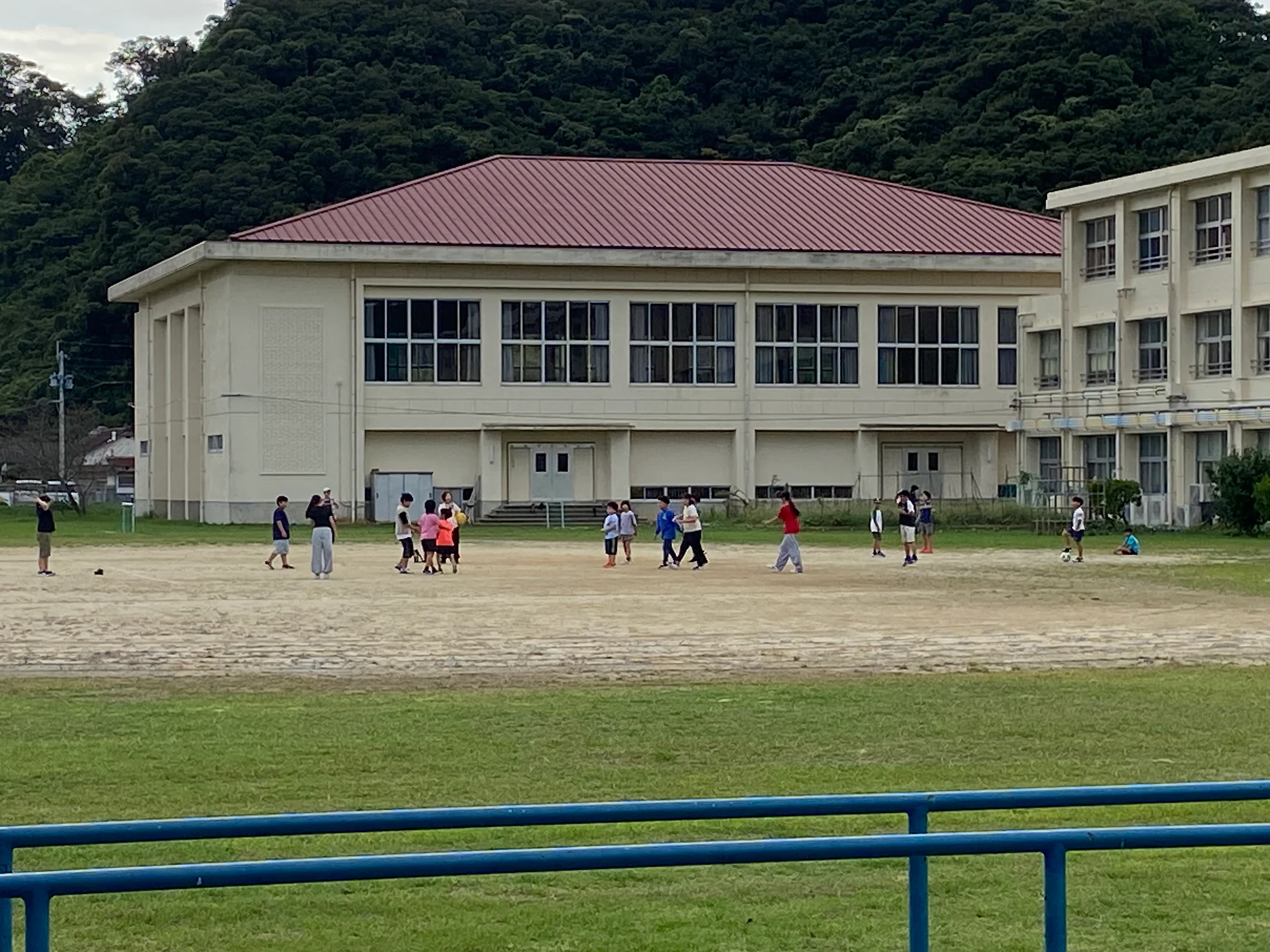 在大島小學校體育館前的運動場上玩球的孩子們